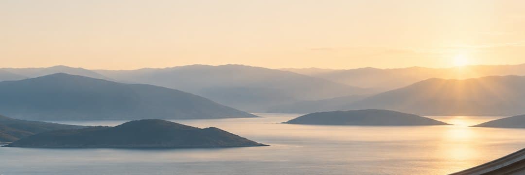 A calm sea and distant mountains at sunrise, from the platform's own panorama